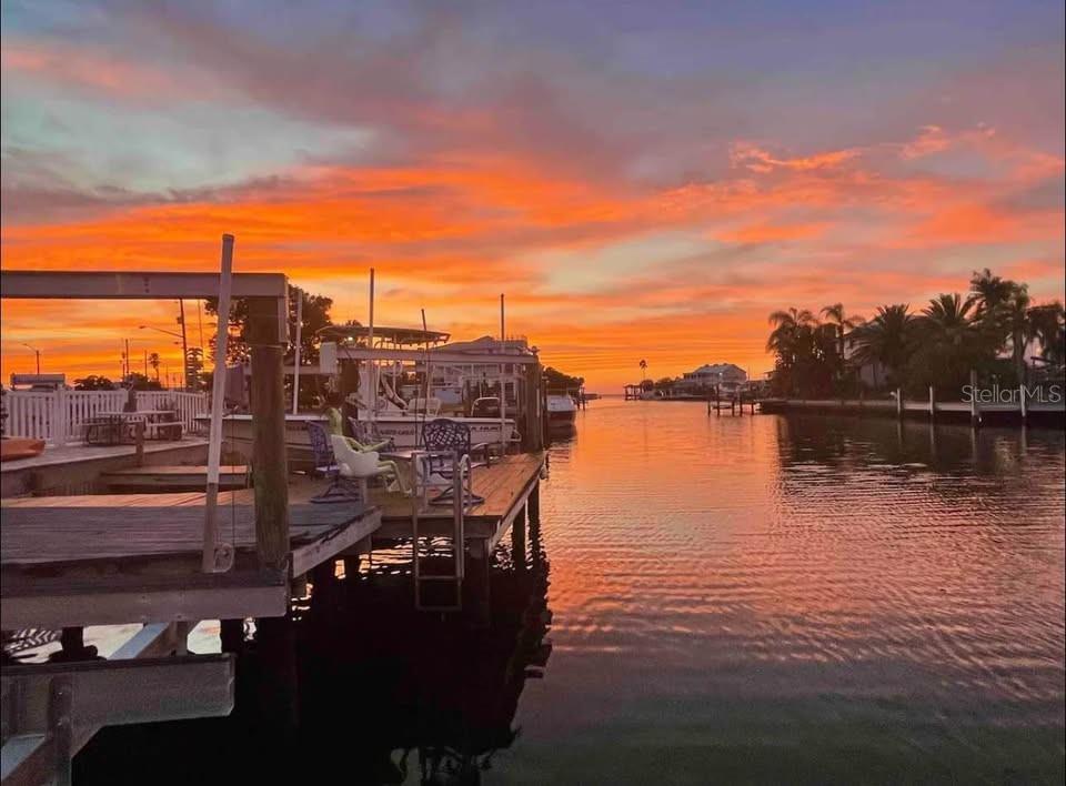 A wooden boat dock overlooks a canal during a vibrant orange and purple sunset — 6501 CLARK STREET, HUDSON, FL