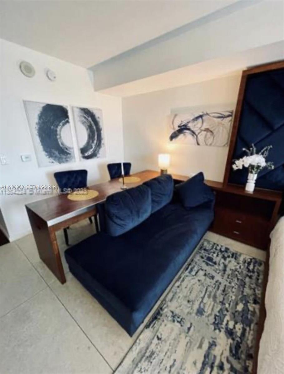 A room features a dark blue sofa placed against a long wooden dining table — 50 Biscayne Blvd # 607, Miami FL 33132, MIAMI, FL