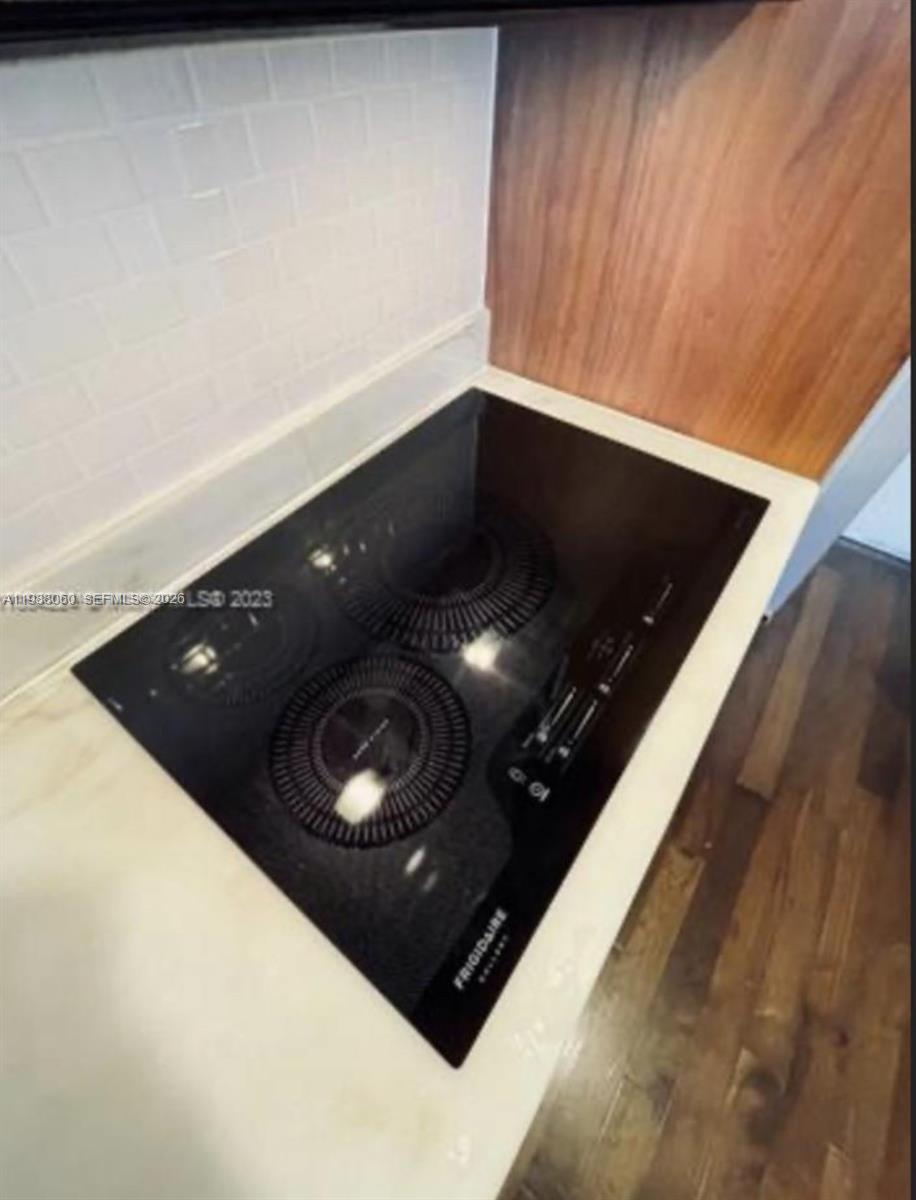 A black Frigidaire induction cooktop is set into a white countertop with a tiled backsplash — 50 Biscayne Blvd # 607, Miami FL 33132, MIAMI, FL