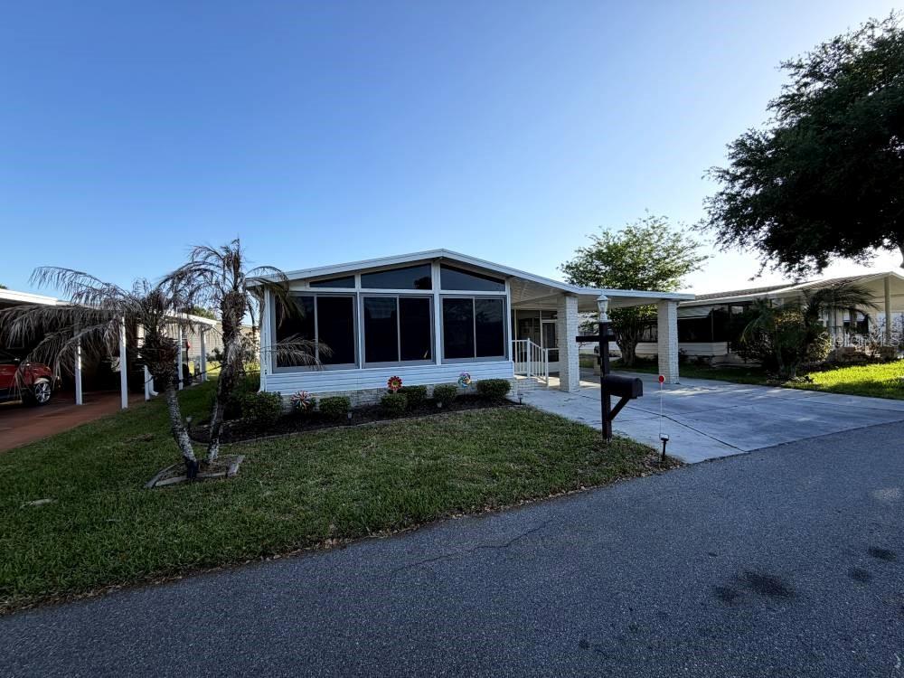 A single-story manufactured home with a screened-in front porch and an attached carport — 161 GREENVIEW DRIVE UNIT 161, WINTER HAVEN, FL