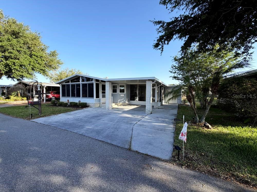 A single-story manufactured home features a screened-in porch, a carport, and a concrete driveway — 161 GREENVIEW DRIVE UNIT 161, WINTER HAVEN, FL