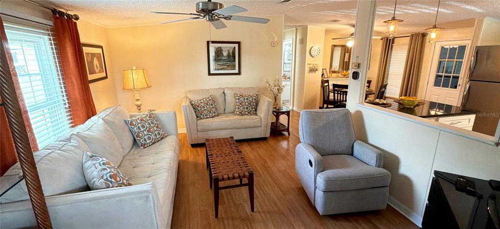 A living room features a sofa, armchair, coffee table, and an open kitchen area — 161 GREENVIEW DRIVE UNIT 161, WINTER HAVEN, FL