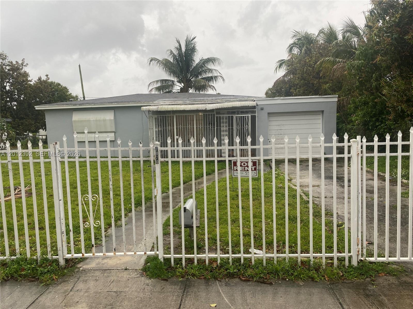 A single-story house with a white fence, a front lawn, and a garage — 1070 NW 147th St, Miami FL 33168, MIAMI, FL