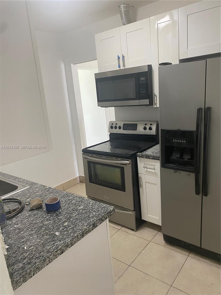 A kitchen features white cabinets, stainless steel appliances, and dark granite countertops — 1070 NW 147th St, Miami FL 33168, MIAMI, FL