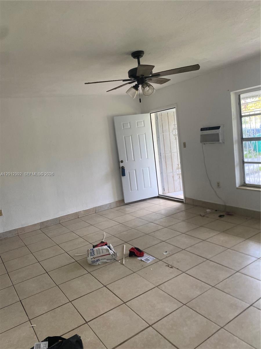 An empty room features white walls, tiled flooring, a ceiling fan, and an open door — 1070 NW 147th St, Miami FL 33168, MIAMI, FL