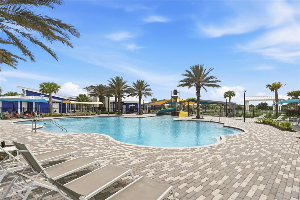 A swimming pool with a slide and lounge chairs on a paved deck with palm trees — 11558 BUOY POINT PLACE, ORLANDO, FL