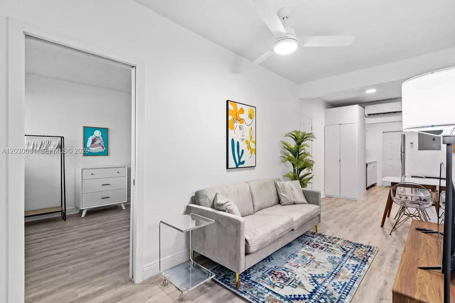 A living room features a gray sofa, a patterned rug, and an adjacent bedroom area — 7325 Carlyle Ave # 2, Miami Beach FL 33141, MIAMI BEACH, FL