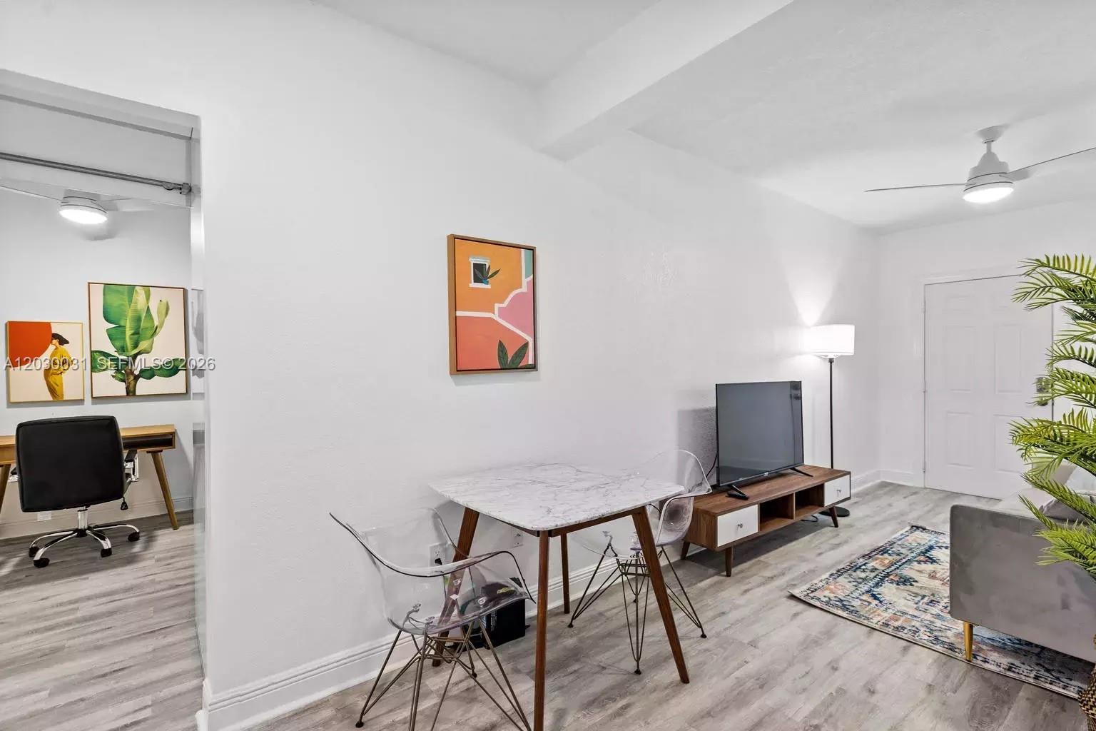 A living area features a dining table, television console, and a view into an office — 7325 Carlyle Ave # 2, Miami Beach FL 33141, MIAMI BEACH, FL