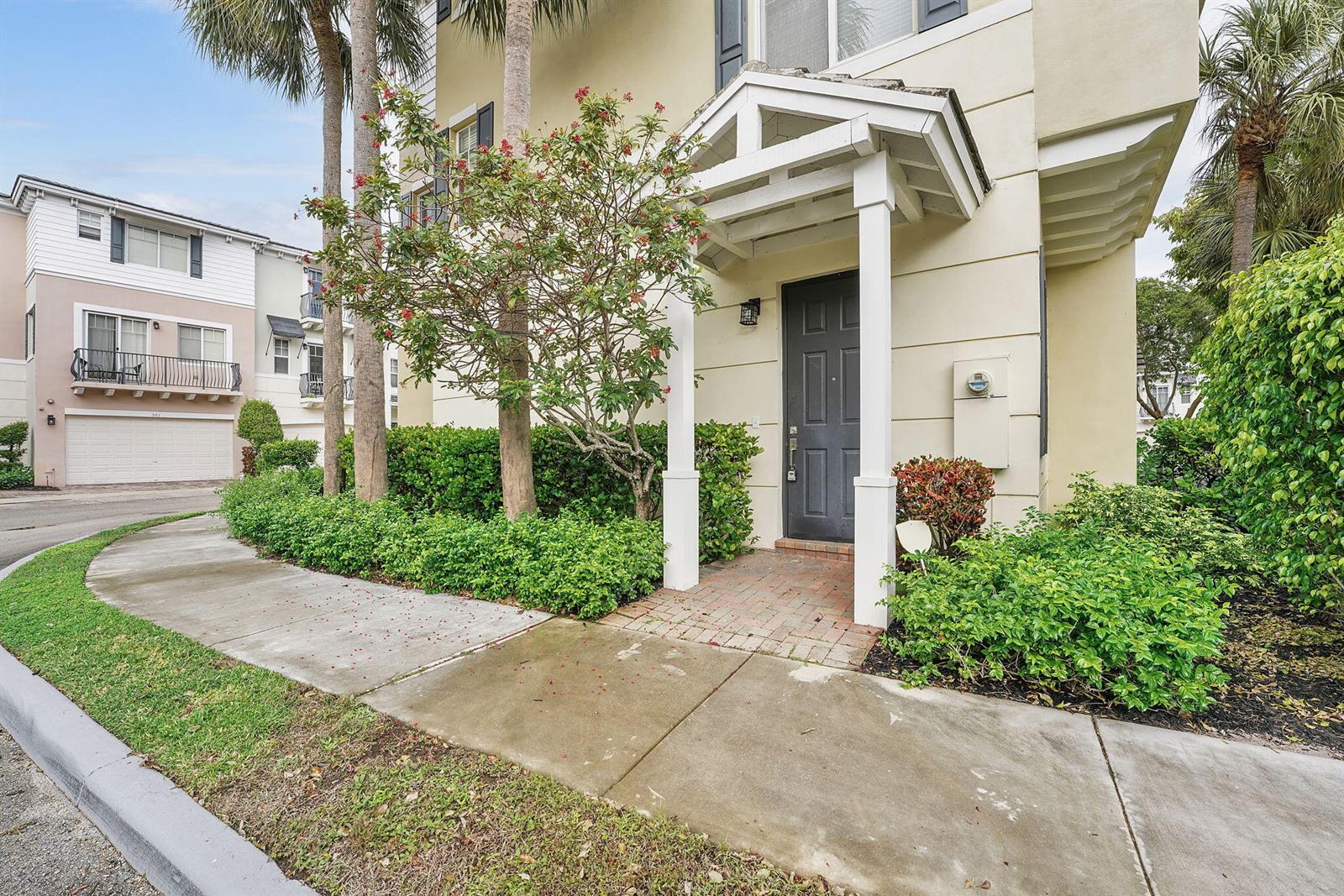 A beige multi-story townhouse features a dark front door under a white covered entryway — 560 NW 39th Circle # 560, Boca Raton FL 33431, BOCA RATON, FL