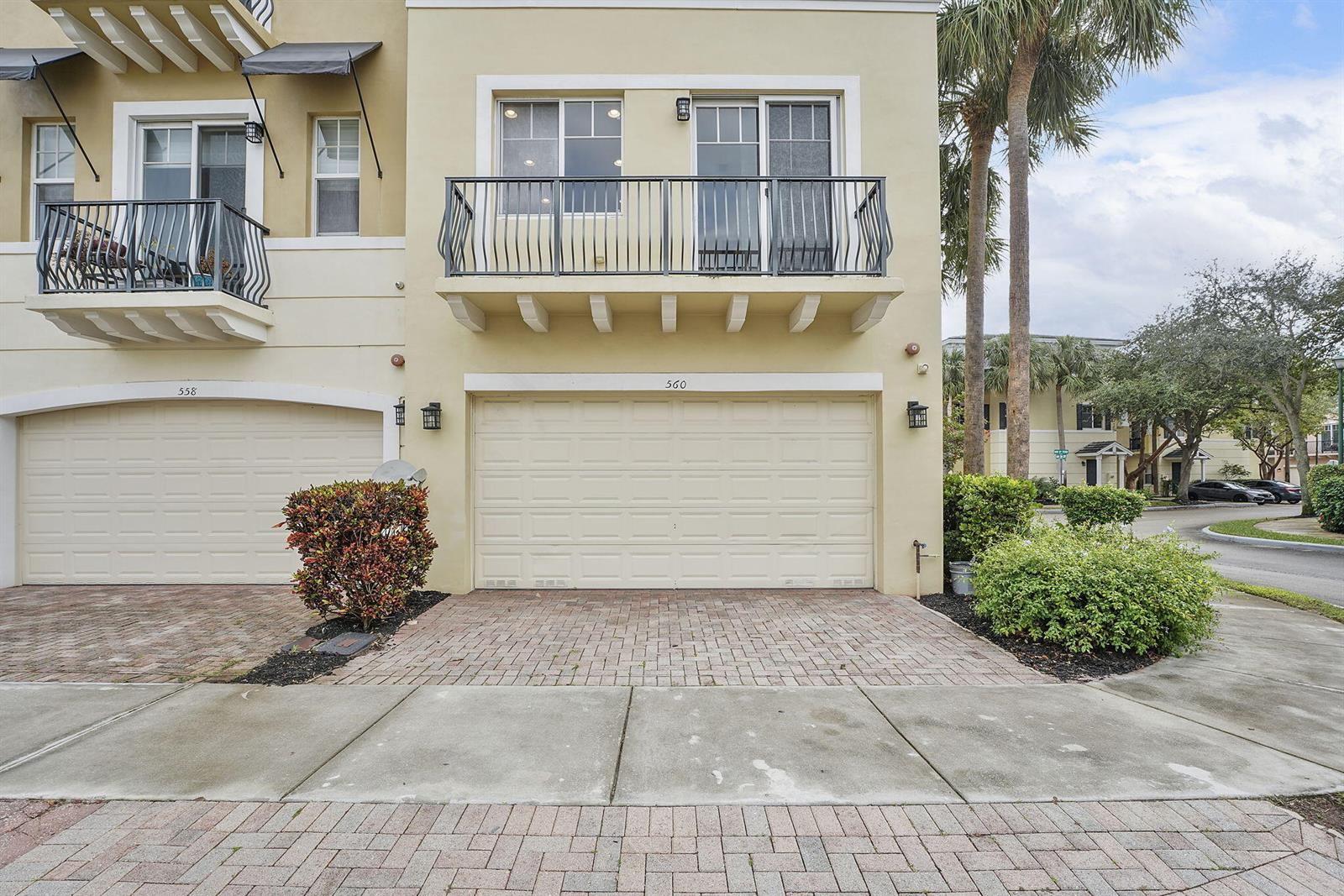 A two-story townhouse exterior features a beige facade, two balconies, and a double garage — 560 NW 39th Circle # 560, Boca Raton FL 33431, BOCA RATON, FL