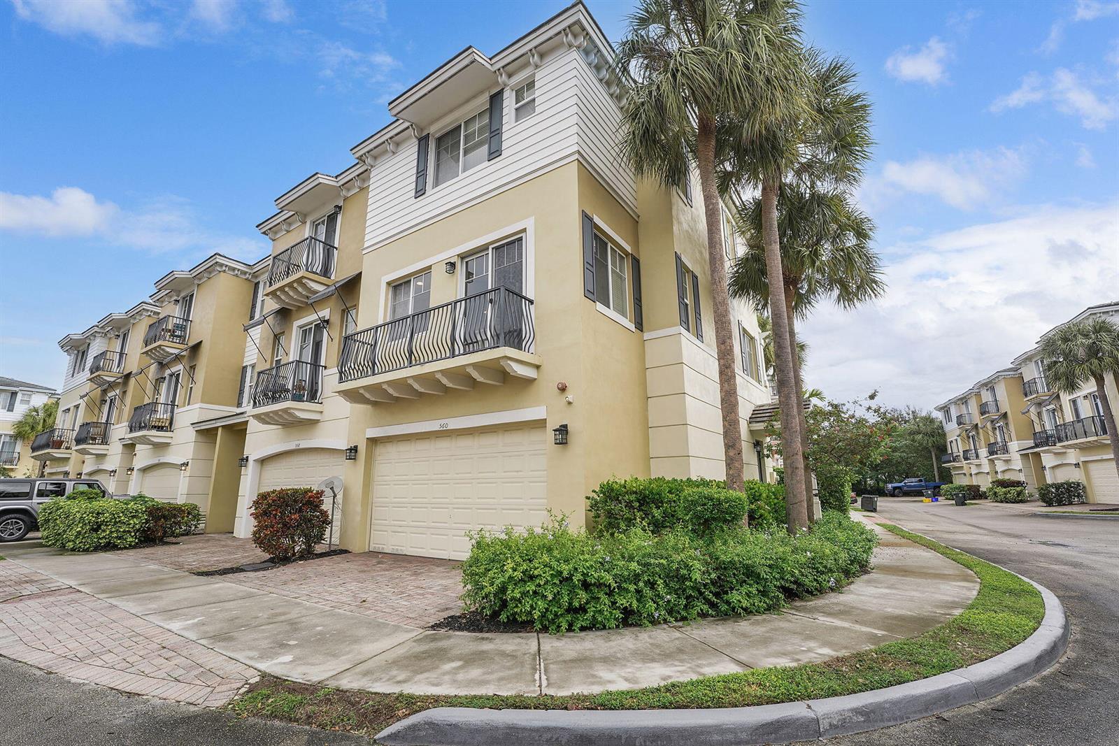 A three-story townhouse with a beige stucco exterior, a two-car garage, and a balcony — 560 NW 39th Circle # 560, Boca Raton FL 33431, BOCA RATON, FL