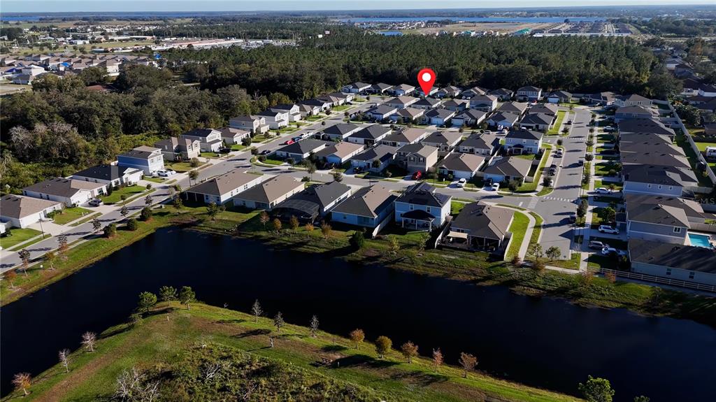 An aerial view shows a residential neighborhood with houses surrounding a pond — 1857 GOLD CREST DRIVE, ST CLOUD, FL
