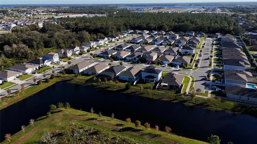 An aerial view shows a suburban neighborhood with houses bordering a large retention pond — 1857 GOLD CREST DRIVE, ST CLOUD, FL