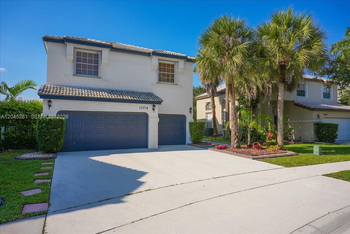 A two-story house with a white stucco exterior and a dark blue garage door — PEMBROKE PINES, FL