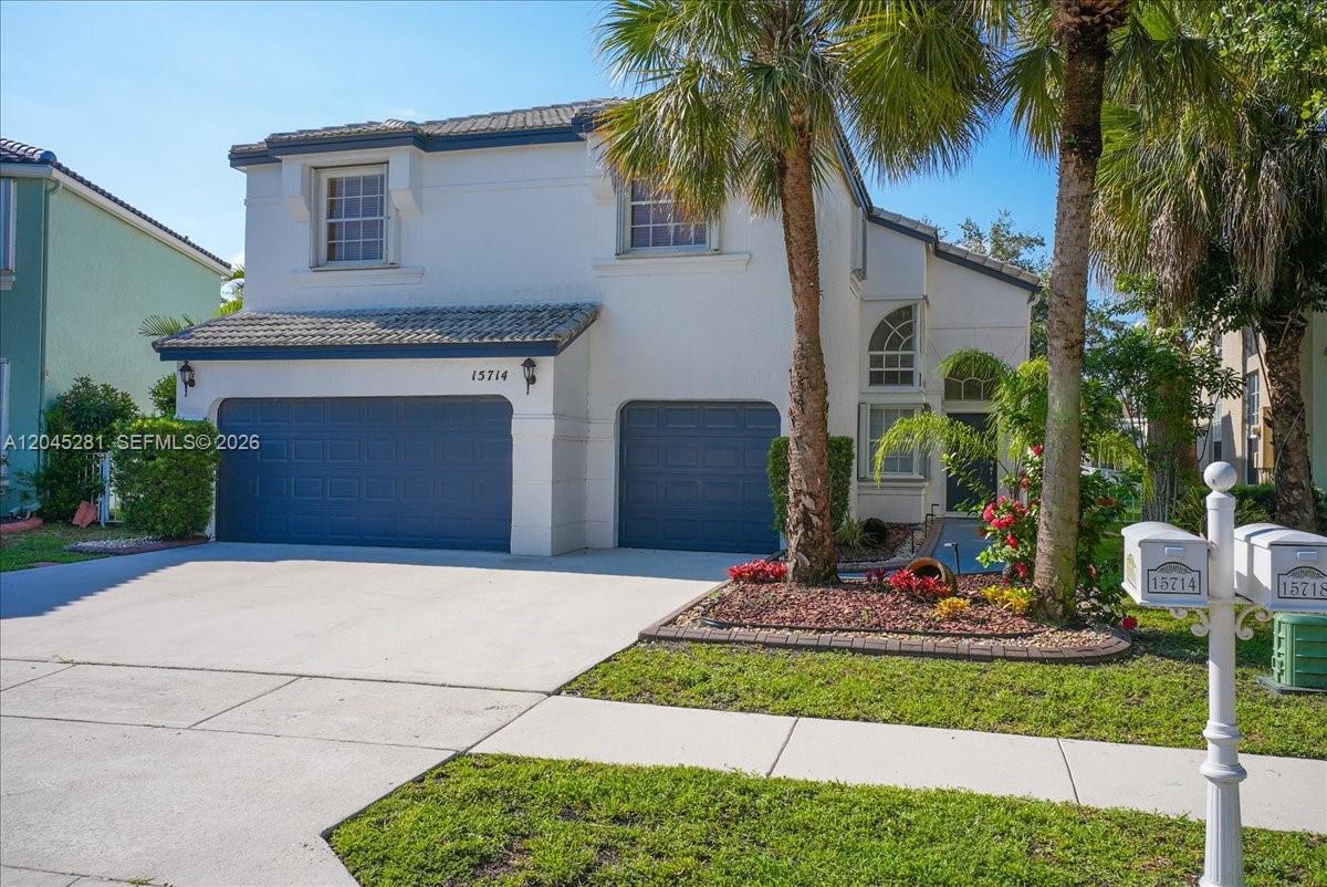 A two-story house features a white exterior, a three-car garage, and a palm tree — PEMBROKE PINES, FL