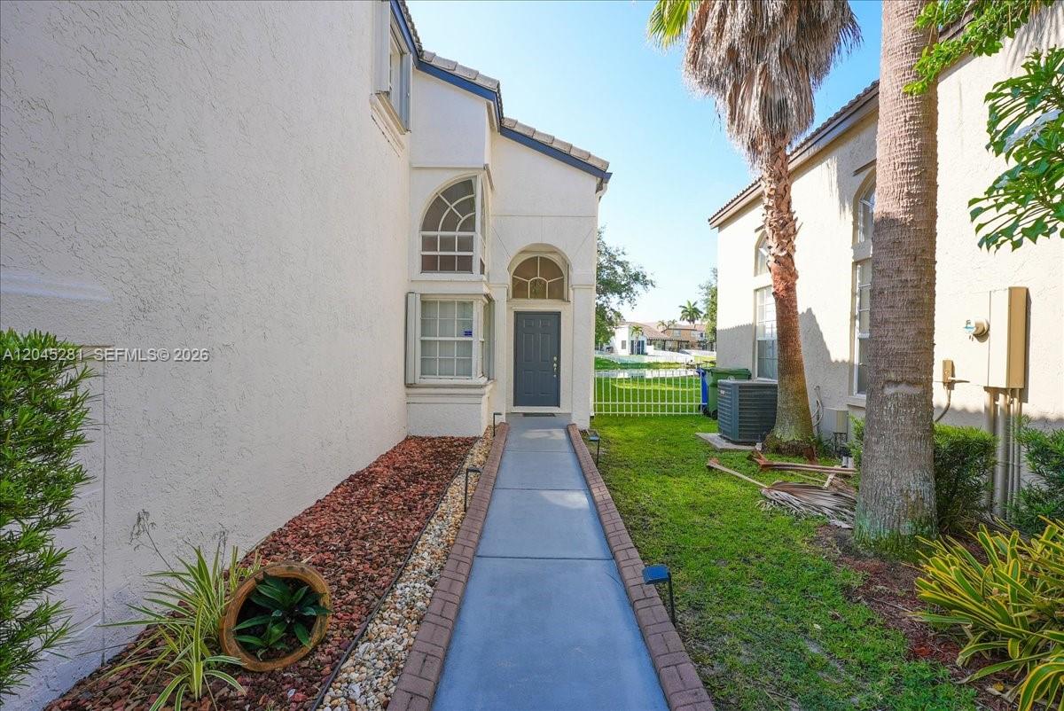 A concrete walkway leads to the front entrance of a two-story stucco home — PEMBROKE PINES, FL