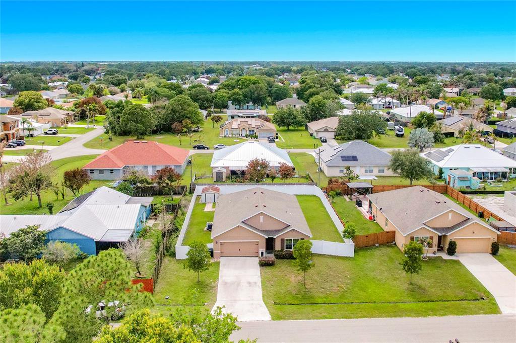 An aerial view shows a suburban neighborhood with single-family homes, green lawns, and paved streets — 1190 SW BROADVIEW STREET, PORT ST LUCIE, FL