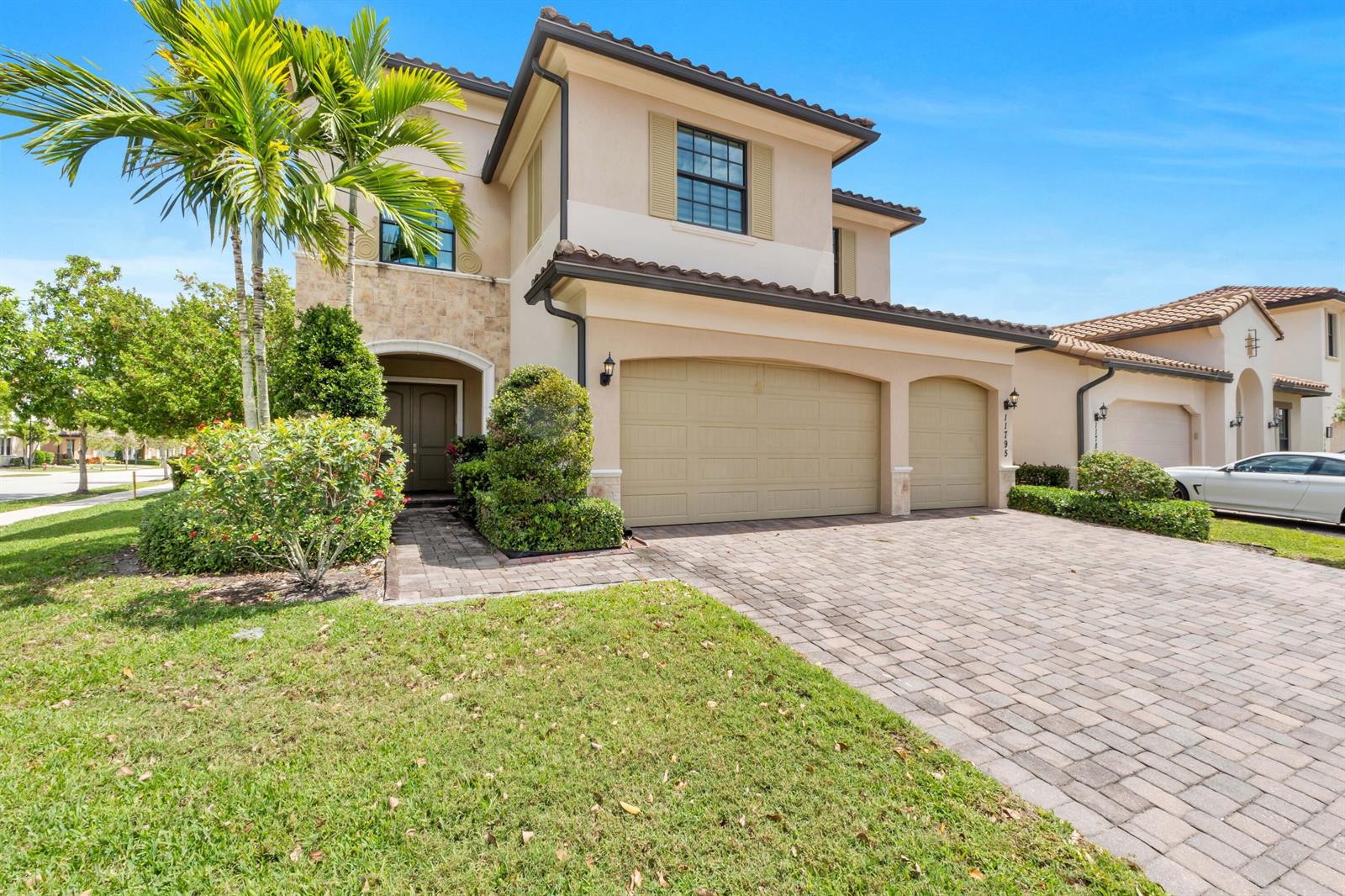 A two-story stucco house features a three-car garage, a paver driveway, and a palm tree — 11795 Waterway Circle, Parkland FL 33076, PARKLAND, FL