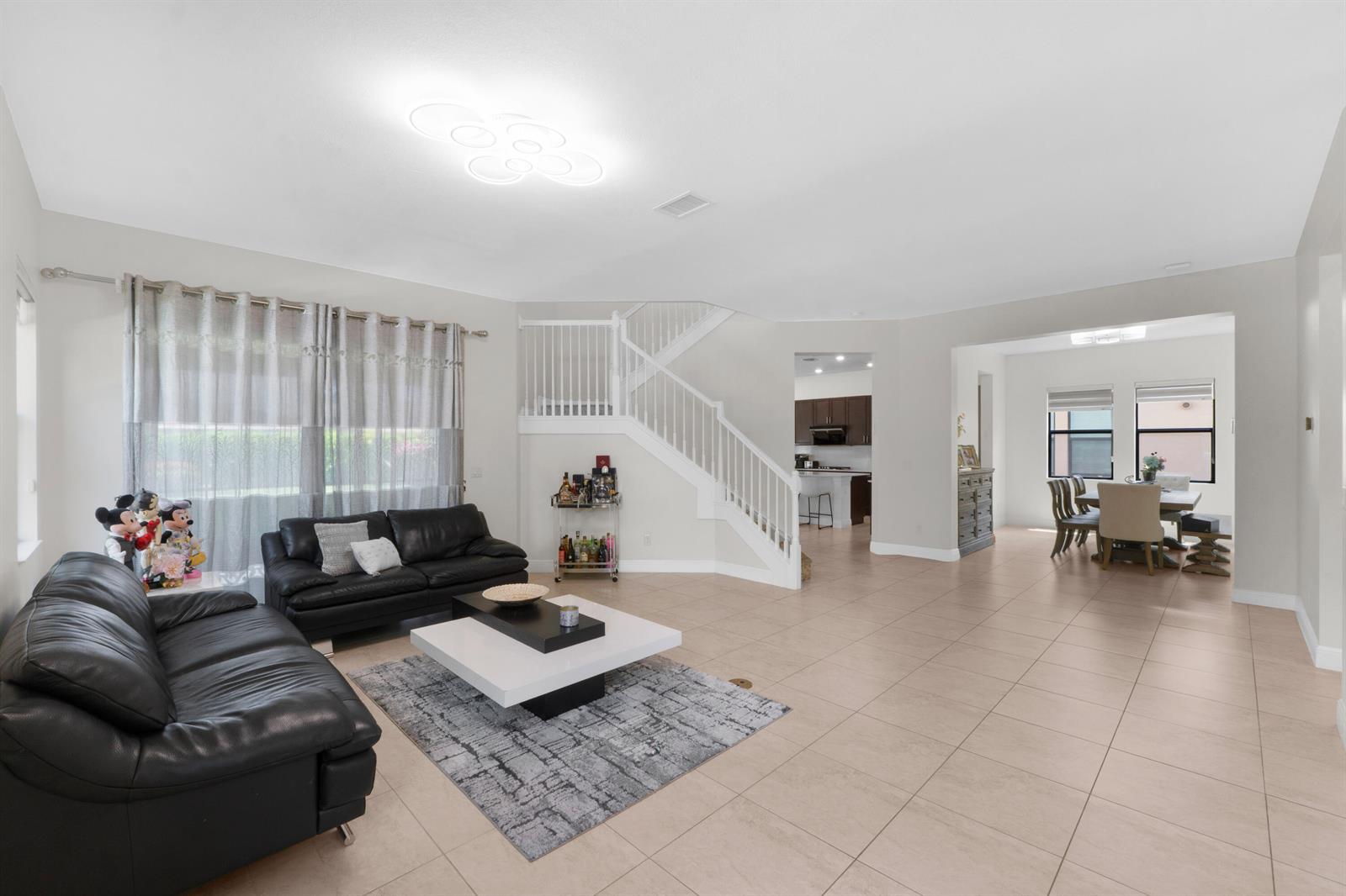 A living room with tile flooring, a staircase, and a dining area in the background — 11795 Waterway Circle, Parkland FL 33076, PARKLAND, FL