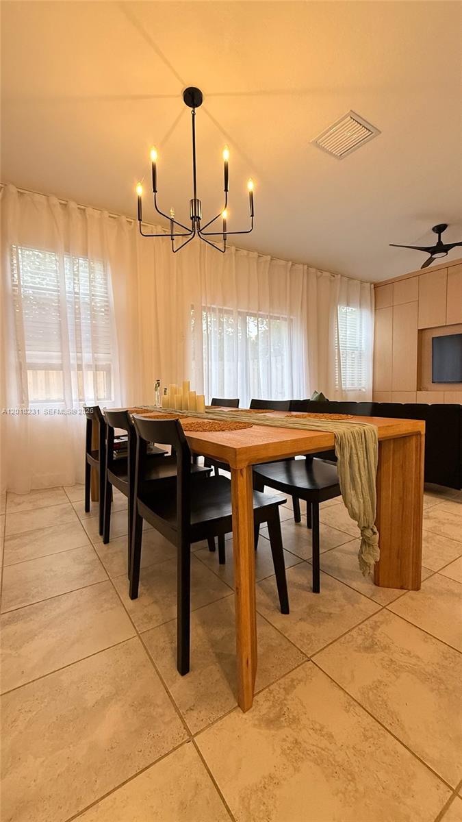 A dining room features a wooden table with black chairs under a modern chandelier — 20761 NE 2nd Ct, Miami FL 33179, MIAMI, FL