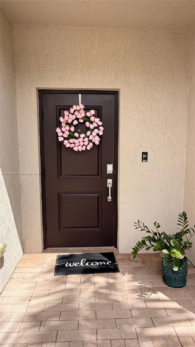A dark brown front door with a tulip wreath sits on a paved entryway — 20761 NE 2nd Ct, Miami FL 33179, MIAMI, FL