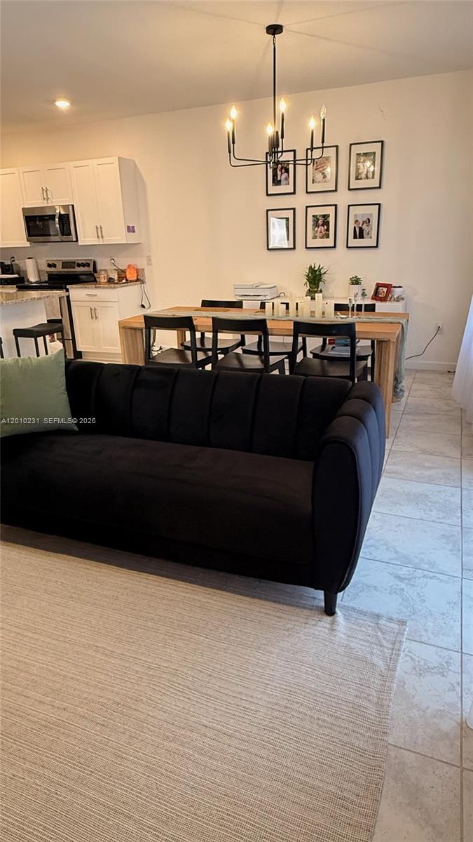 A living room features a black velvet sofa, a dining table, and white kitchen cabinets — 20761 NE 2nd Ct, Miami FL 33179, MIAMI, FL