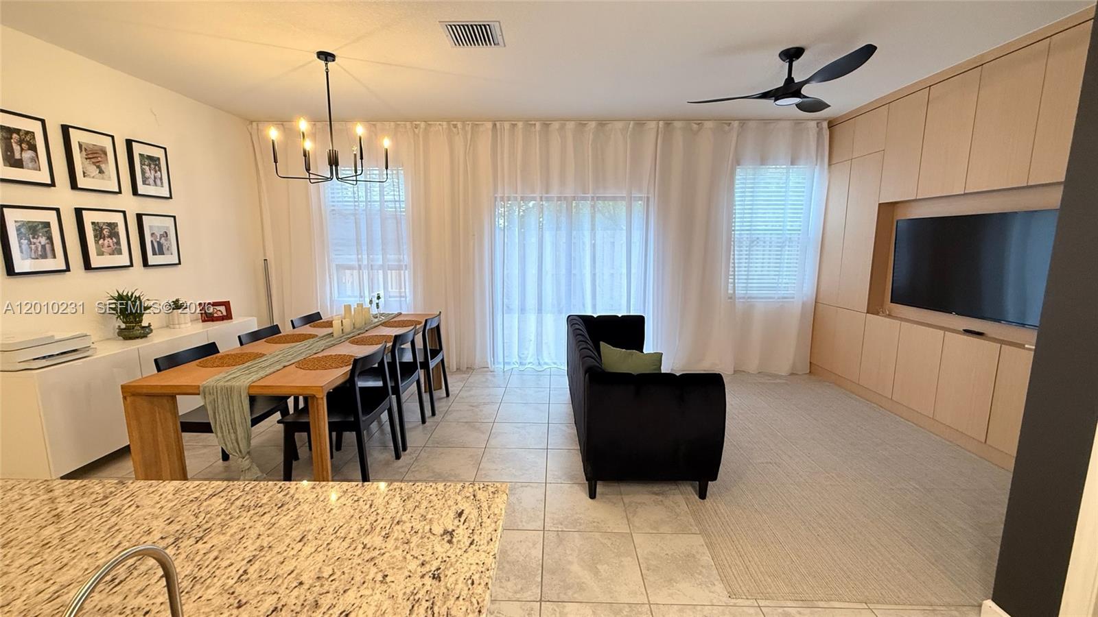 A dining area and living room feature a wooden table, black sofa, and built-in cabinetry — 20761 NE 2nd Ct, Miami FL 33179, MIAMI, FL