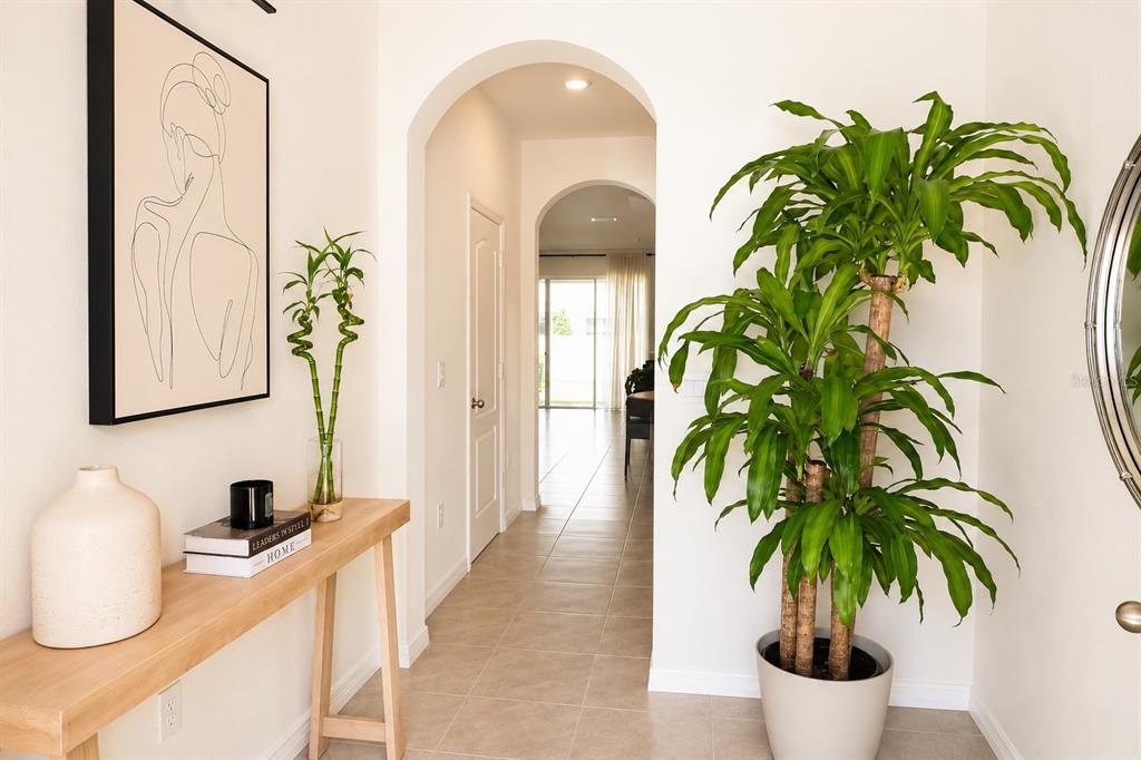 A bright entryway features a console table, a large potted plant, and arched doorways — 2238 TAY WES DRIVE, ST CLOUD, FL