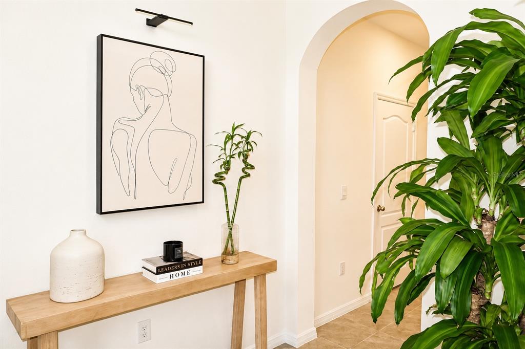 A console table with decor sits in a hallway next to a large potted plant — 2238 TAY WES DRIVE, ST CLOUD, FL