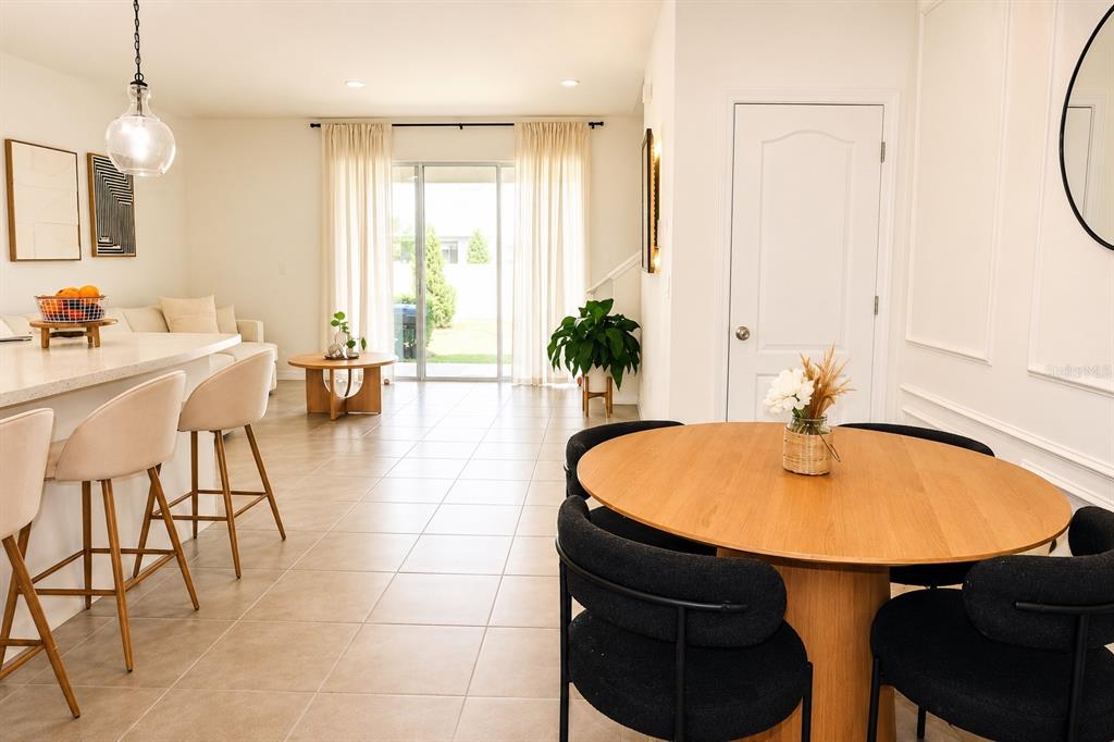 A bright open-concept living and dining area features tile floors, a kitchen island, and patio doors — 2238 TAY WES DRIVE, ST CLOUD, FL