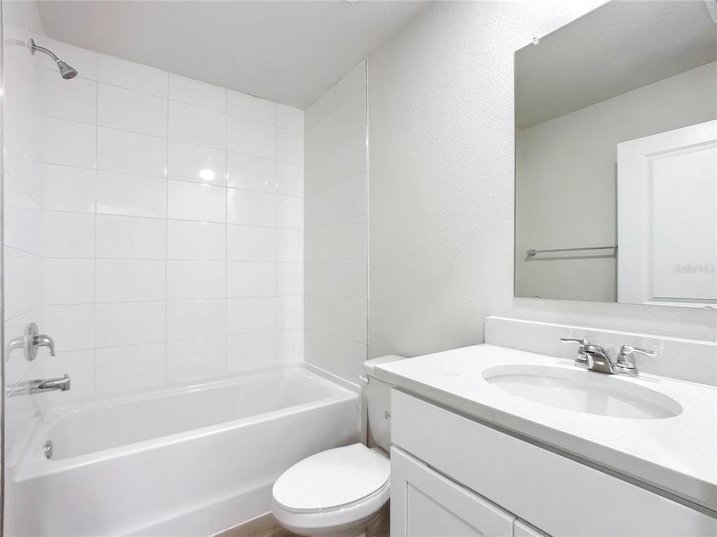 A bathroom features a white vanity, a toilet, and a bathtub with white wall tiles — 54 UNDERWOOD TRAIL, PALM COAST, FL