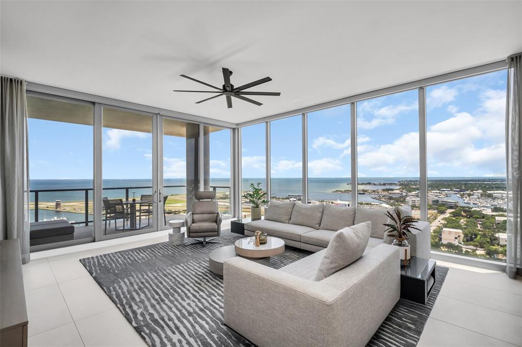 A modern living room features floor-to-ceiling windows with panoramic ocean and coastal city views — 301 1ST STREET S UNIT 2501, ST PETERSBURG, FL