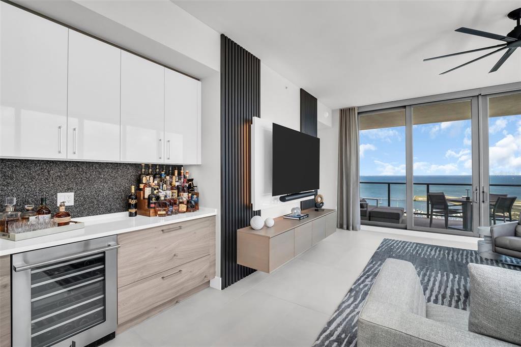 A modern living room features a wet bar, a wall-mounted television, and a balcony view — 301 1ST STREET S UNIT 2501, ST PETERSBURG, FL