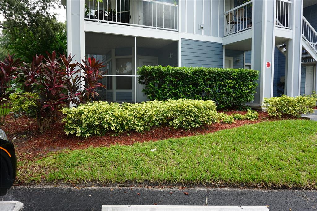 A multi-story apartment building exterior features a screened-in patio, landscaping, and a grassy lawn — 732 SECRET HARBOR LANE UNIT 100, LAKE MARY, FL