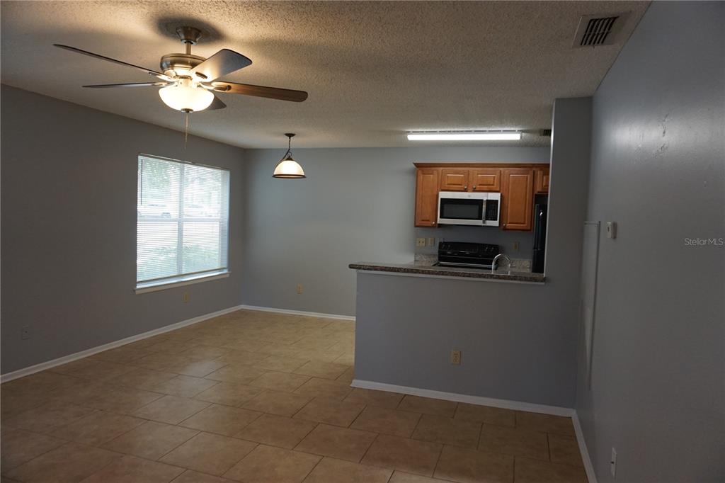 An open-concept kitchen and dining area features tile flooring, light gray walls, and wood cabinets — 732 SECRET HARBOR LANE UNIT 100, LAKE MARY, FL