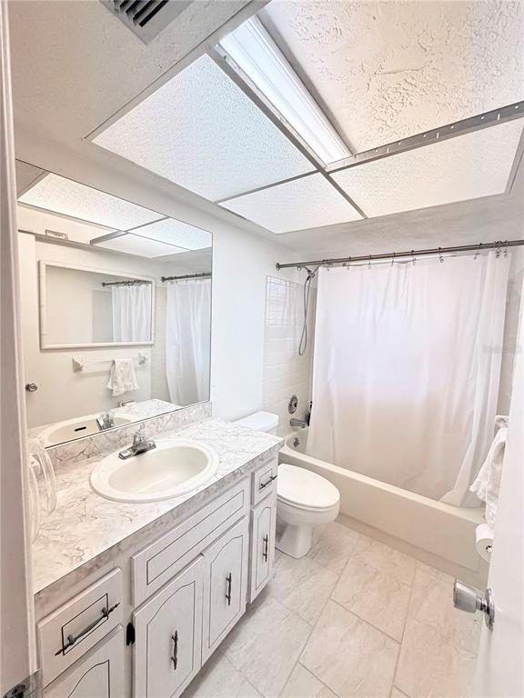 A bathroom features a white vanity, a tub-shower combination, and a large ceiling light panel — 7016 CUTTY SARK DRIVE, PORT RICHEY, FL