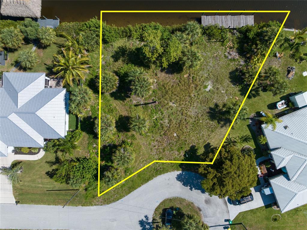 An aerial view shows a vacant, irregularly shaped waterfront lot outlined in yellow — 19188 NEW HAVEN COURT, PORT CHARLOTTE, FL