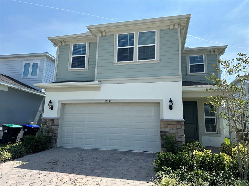 A two-story house with a light-colored garage, stone accents, and light blue siding — 10355 PARKVIEW RESERVE LANE, ORLANDO, FL