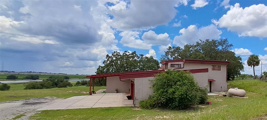 A red pergola extends from a beige house with two red garage doors — 2741 EDWARDS ROAD, HAINES CITY, FL