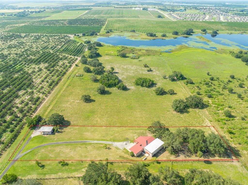 A two-story house with a red roof and a concrete patio overlooks a grassy field — 2741 EDWARDS ROAD, HAINES CITY, FL