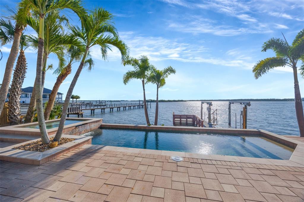 A backyard pool and spa overlook a wooden dock on a large body of water — 8400 35TH AVENUE N, ST PETERSBURG, FL
