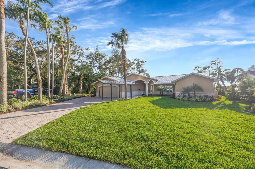 A single-story house with a metal roof, a paved driveway, and palm trees in front — 8400 35TH AVENUE N, ST PETERSBURG, FL