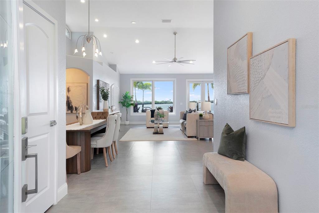 An open-concept living and dining area features light tile flooring, vaulted ceilings, and waterfront views — 8400 35TH AVENUE N, ST PETERSBURG, FL