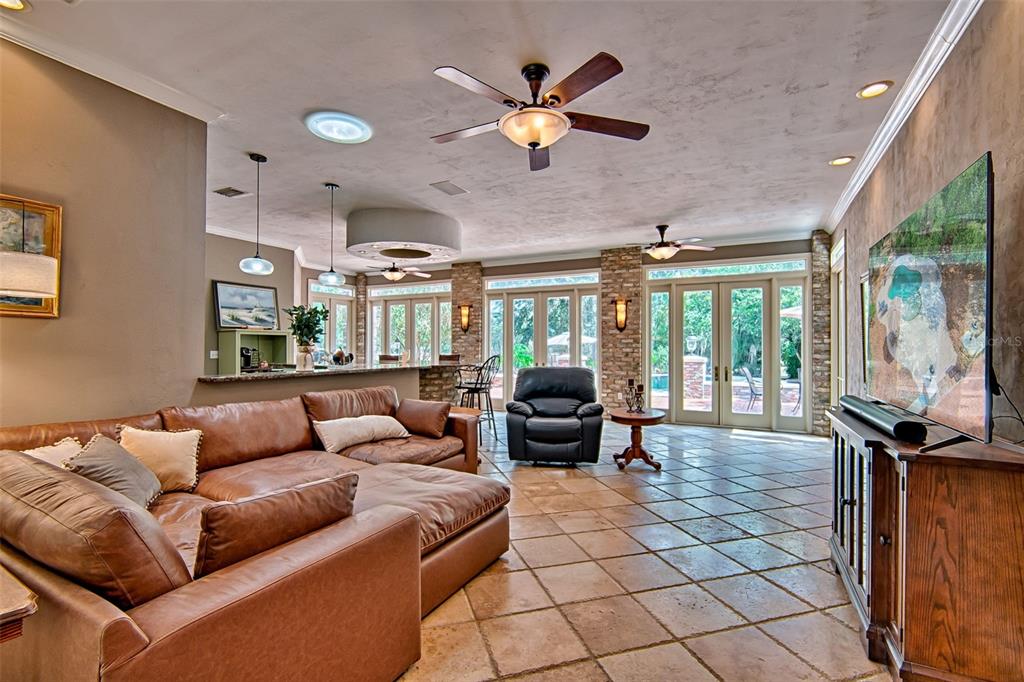A spacious living room features a large leather sectional, tile flooring, and glass patio doors — 12208 SW 9TH AVENUE, NEWBERRY, FL