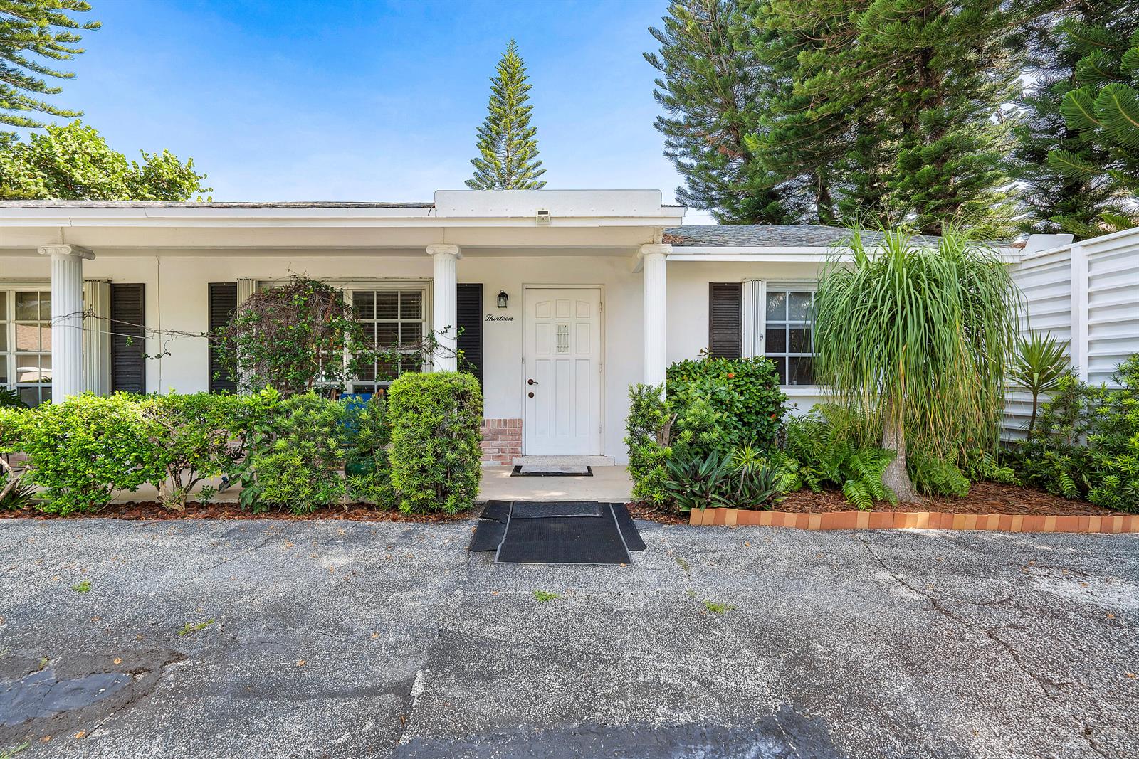 The exterior of a white, single-story house features a front door, columns, and landscaping — 11 Sailfish Lane, Ocean Ridge FL 33435, OCEAN RIDGE, FL