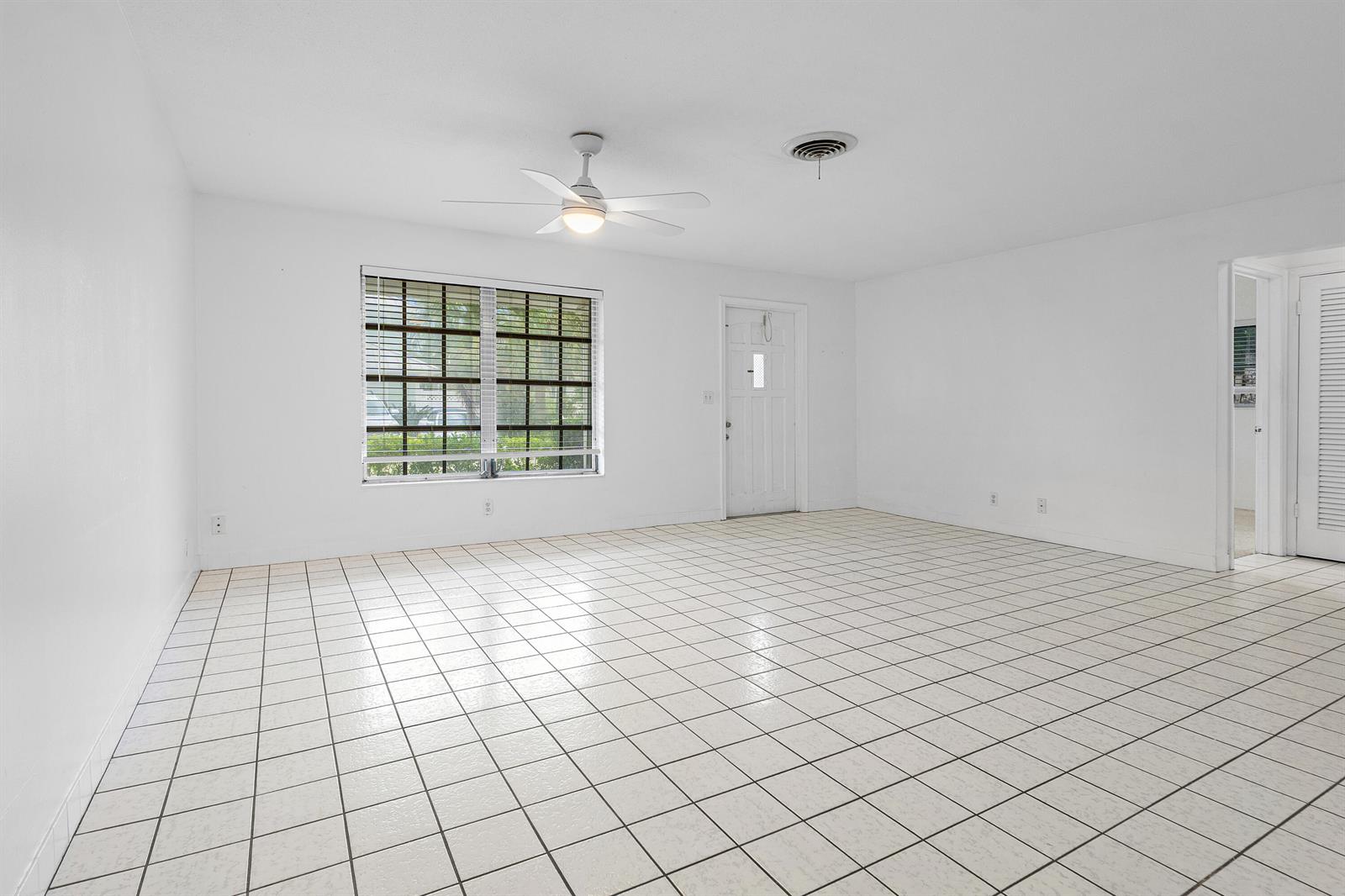 A bright, empty room features white walls, white tiled flooring, a ceiling fan, and a window — 11 Sailfish Lane, Ocean Ridge FL 33435, OCEAN RIDGE, FL