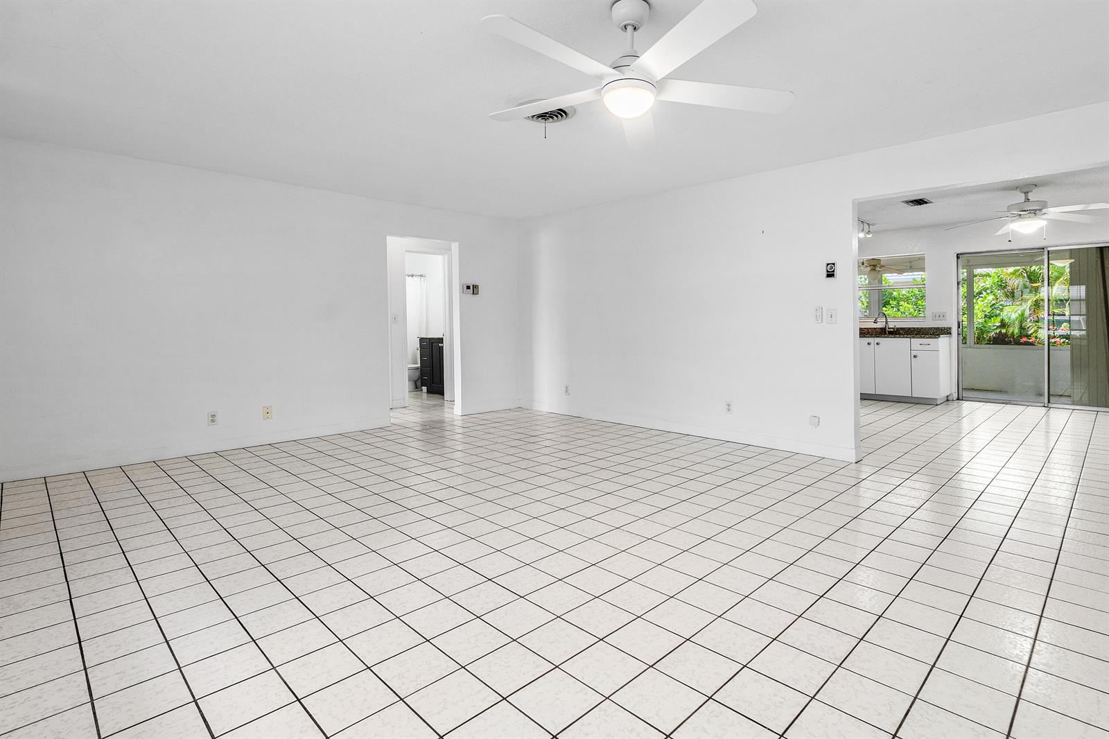 A bright, open-concept living area features white walls, white tiled floors, and a ceiling fan — 11 Sailfish Lane, Ocean Ridge FL 33435, OCEAN RIDGE, FL