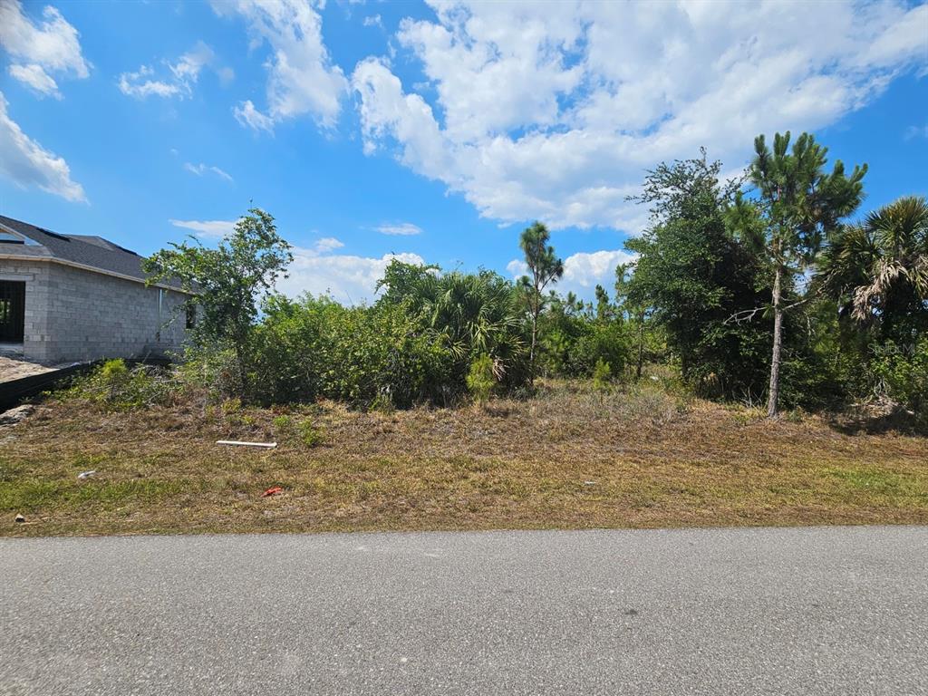 A vacant, overgrown residential lot sits next to a house under construction — 15723 STUART CIRCLE, PORT CHARLOTTE, FL