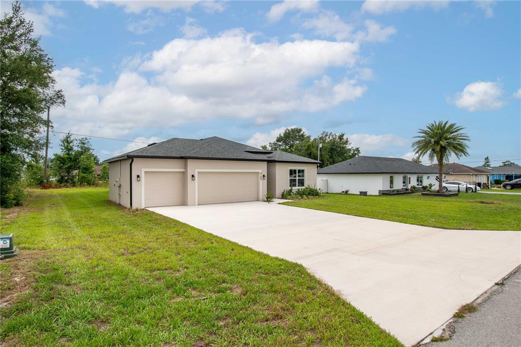 A beige single-story house with a three-car garage and a concrete driveway — 4780 SW 129TH PLACE, OCALA, FL