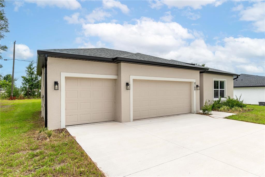 A beige single-story house features a three-car garage and a concrete driveway — 4780 SW 129TH PLACE, OCALA, FL